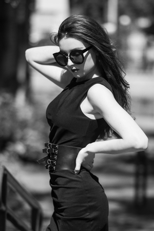 portrait of elegant woman in black dress walking in cityの写真素材