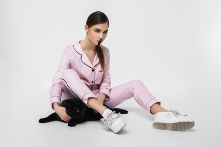 young pretty woman in pink pajama with cat