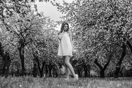 Beautiful woman enjoying sunny spring day in park during cherry blossom seasonの写真素材