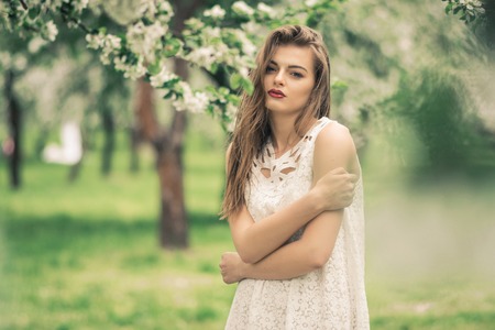 Beautiful woman enjoying sunny spring day in park during cherry blossom seasonの写真素材