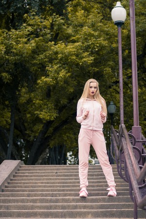 tired girl in a sports suit sits on the stepsの写真素材