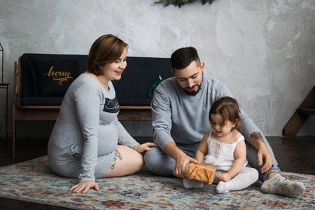 Little girl and his parents kissing. Pregnant woman. So happy familyの写真素材