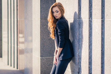 Outdoors fashion portrait of trendy pretty girl posing on the wall background.の写真素材