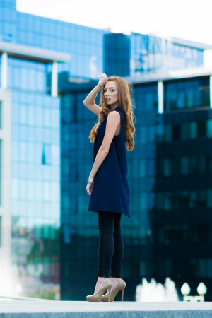 Happy woman standing outdoors in business casual suite against modern mallの写真素材