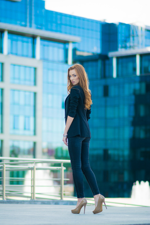 Happy woman standing outdoors in business casual suite against modern mallの写真素材