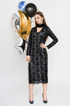 Joyful young woman in luxury dress on heels celebrating new year in studio. Having fun with balloonsの写真素材
