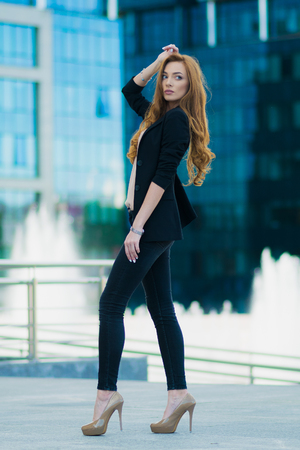 Happy woman standing outdoors in business casual suite against modern mallの写真素材