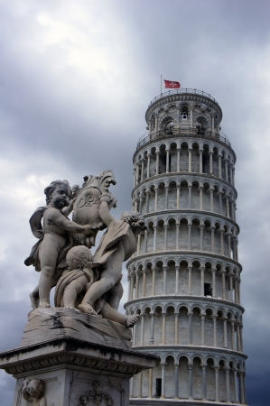 Statues of cherubs angel and Leaning Tower in Pisa, Italyの写真素材