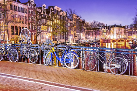 Bicycles parked on a bridge in Amsterdam at night, The Netherlandsの写真素材