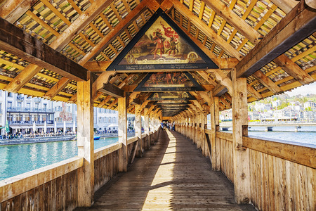 LUCERNE, SWITZERLAND - APRIL 10, 2017: Inside view of Ð°ncient covered wooden Chapel Bridge Kapellbrucke over Reuss River in the historic center of Lucerne at sunset, Switzerland.のeditorial素材
