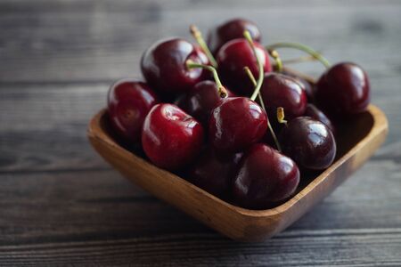 Ripe fresh cherries in a wooden bowl. Food background. Red juicy cherry berry on grey wooden background. Cherries in a dish closeup.の写真素材