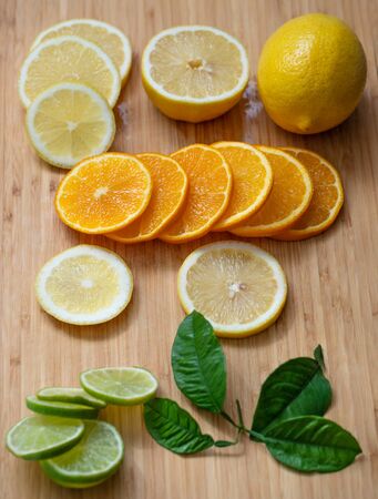Sliced citrus fruit on a wooden chopping Board. Juicy ripe slices of orange, lemon and lime on wooden background. Fruit mix.の写真素材