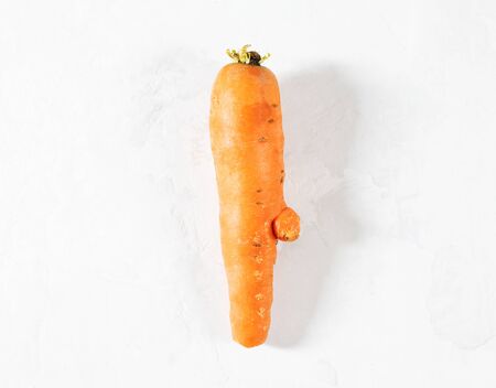 Trendy ugly food concept. Funny carrot on a white background. Vegetable with a strange shape. The problem of food waste. Top view, flat lay. Copy space.の写真素材
