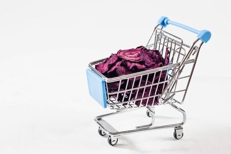 Dried beet chips in a toy grocery cart on a white background. Organic natural food. Concept vegan shopping. Copy space.の写真素材