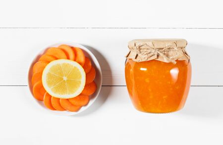 Delicious homemade carrot jam with lemon in a glass jar on a white wooden background. Top view, flat lay.の写真素材