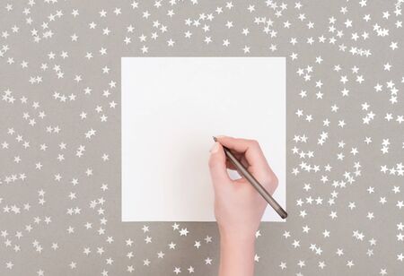 Christmas mockup with silver confetti stars on grey background. Wish list for Christmas. Happy New Year. Top view, flat lay. Greeting card. Copy space, template.の写真素材