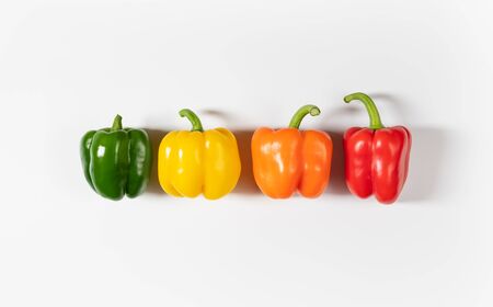Colored bell peppers on white background. Green, yellow, orange and red pepper. Food concept. Top view.の写真素材