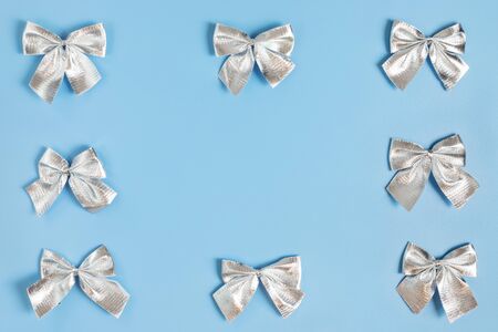 Christmas border with silver bows on pastel blue background.の写真素材