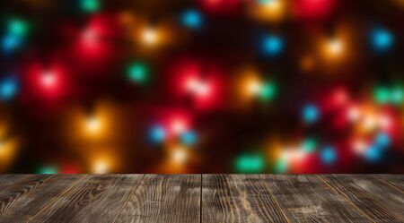 Empty wooden tabletop against a background of colorful blurred garlands. Image for montage or...