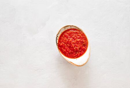 Hot chili pepper sauce paste harissa. Adjika on a white background. Traditional Tunisia, Georgian and Arabic cuisine. Homemade rose harissa in a bowl. Copy space. Flat lay, top view.の写真素材