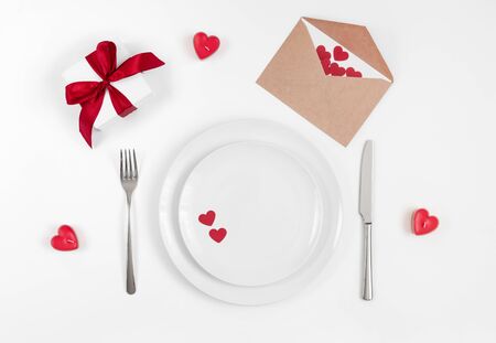 Valentines day or romantic dinner background. Festive romantic table setting with candles and a gift on a white background. Valentine's card. Copy space, top view, flat lay.の写真素材