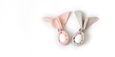 Easter decoration with rabbits napkins and eggs on a white background. Easter concert. Banner. Copy space, top view, flat lay.の写真素材