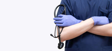 A doctor in a blue uniform with a stethoscope on a white background. Banner, copy space. Coronavirus, covid-19, healthcare concept.の写真素材