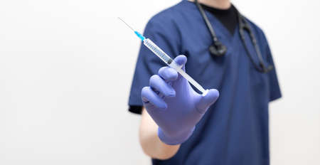 Doctor with a syringe on a white background. Banner. Vaccination. Coronavirus, covid-19, healthcare concept. Close-up of the syringe.の写真素材
