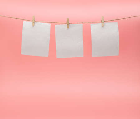 Toilet paper hanging to dry on a clothesline on a pink background. The concept of saving money. Copy...