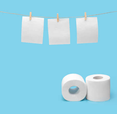 Toilet paper hangs to dry on a clothesline. Toilet paper rolls on a blue background. The concept of saving money. Copy space.の写真素材