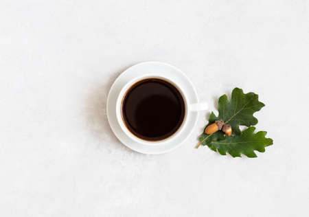 Black coffee with oak leaves and acorns on a white background. A cup of acorn coffee. Caffeine substitute concept. Top view, flat lay, copy space.の写真素材
