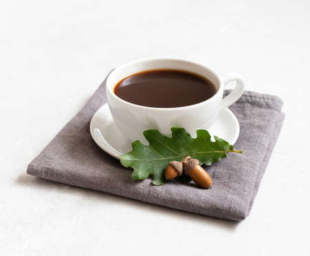 Black coffee on a gray napkin, acorns and oak leaf on a white background. Acorn coffee without caffeine.の写真素材