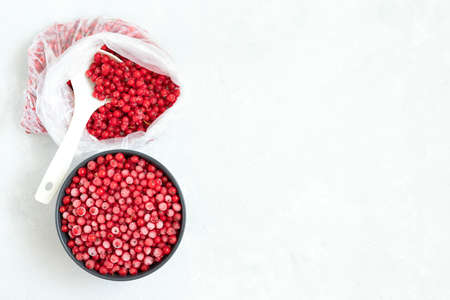 Frozen red currant in a bowl and bag on a white background. Berries in the shape of a heart. Healthy eating concept. Copy space, view from above.の写真素材