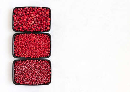 Containers with frozen berries mix on a white background. Storage of frozen food. Cranberries, red currants, lingonberries. Space for text. View from above.の写真素材