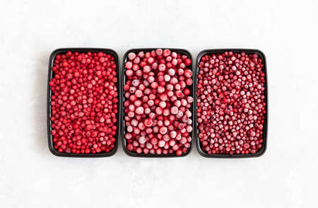 Set of frozen berries in containers on a white background. Cranberries, lingonberries, red currants,...