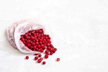 Frozen cranberries in a plastic bag on a white background. Frozen red berries food. Stocks concept. Copy space. Side view.の写真素材