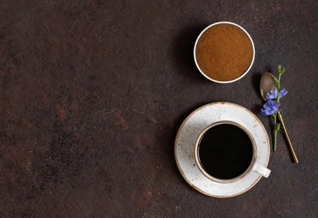Cup with chicory coffee, chicory powder and blue flowers on a brown background. Space for text. Top view, flat lay.の写真素材