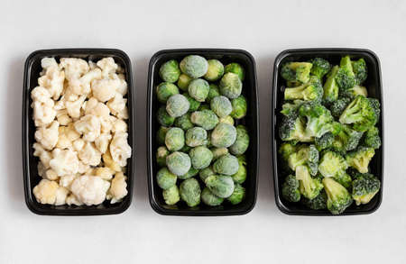 Frozen vegetables in plastic containers on a white background. Cabbage mix. Broccoli, brussels sprouts, cauliflower. View from above.の写真素材
