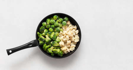 Frozen vegetables in a frying pan on a white background. Cabbage mix. Broccoli, cauliflower, Brussels sprouts. Copy space, top view, flat lay.の写真素材