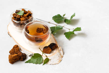 Natural chaga tea in glass bowls. Trendy healthy beverage. Organic drink with birch mushroom. Side...