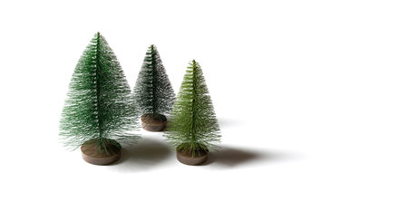 Small artificial Christmas trees isolated on a white background. Minimal winter concept. Banner....