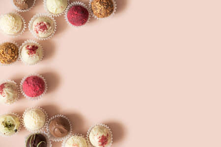 Homemade truffles on a pink background. Energy balls with chocolate, coconut, nuts, berries and...