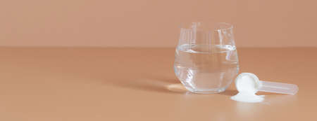 Collagen powder in a measuring spoon and water on a beige background. Banner. Supplement for skin...