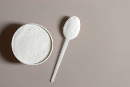 Collagen on a beige background closeup. Collagen protein powder in a bowl. A natural supplement for health and beauty. Copy space, top view, flat lay.の写真素材