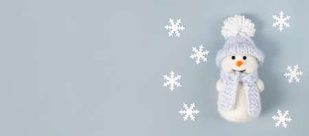 Christmas banner with white snowflakes and a cute snowman on pastel blue background. Copy space, top view, flat lay.の写真素材