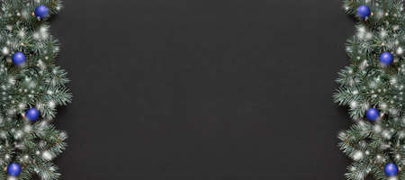 Christmas banner with fir branches, blue balls and snow on black background. View from above. Space for text.の写真素材