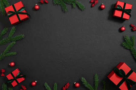 Christmas frame with red gifts, baubles and green fir branches on black background. Winter holiday. Template, mockup. Copy space, top view, flat lay.の写真素材