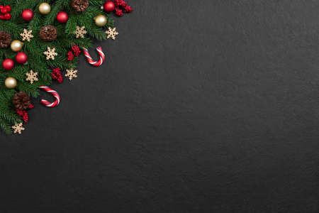Christmas black background with fir branches, red and gold baubles, cones and candy cane. New Year....