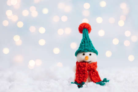 Christmas background with snowman in a green hat and red scarf. Greeting card with a happy toy snowman. Happy New Year. Space for text.の写真素材