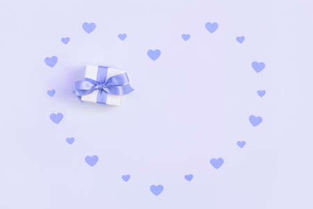 Greeting card for Valentines Day. Small confetti hearts and a gift on a violet background. Trendy color very peri in the 2022 year. Space for text. Top view, flat lay.の写真素材